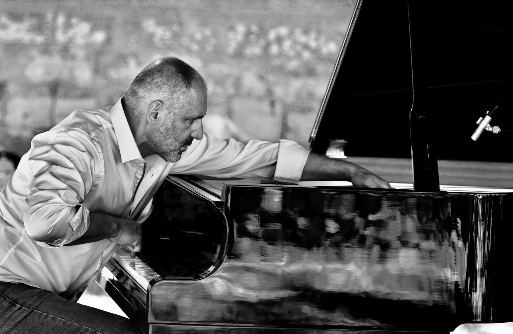 Portrait en noir et blanc de Pascal Neveu penché sur son piano