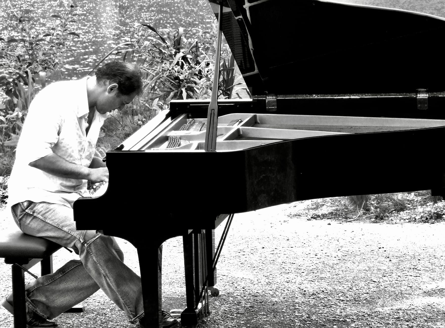 Pascal Neveu au piano en plein air au bord de l'eau (noir et blanc)